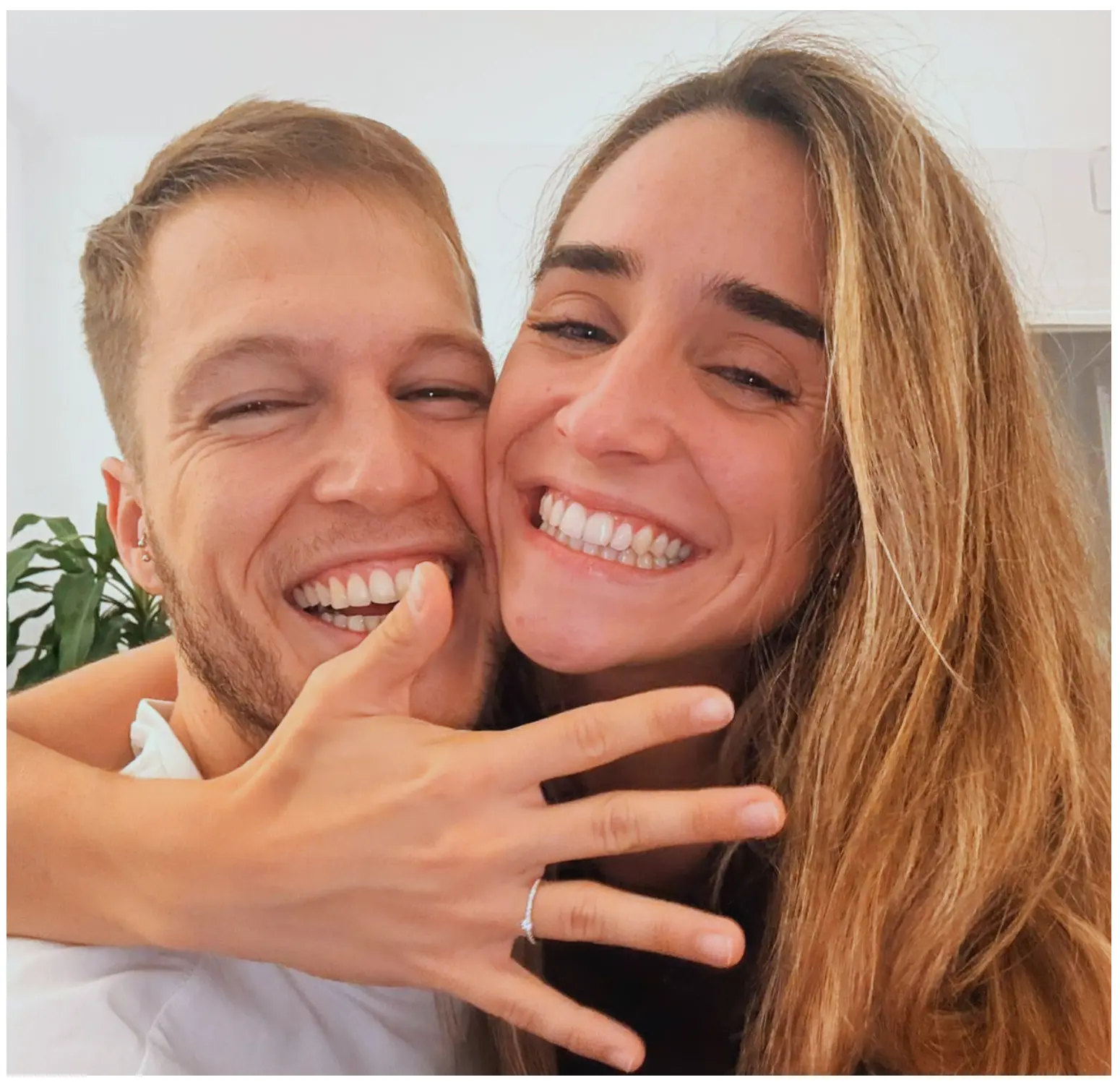 María y Román abrazados, sonriendo y mostrando el anillo de compromiso